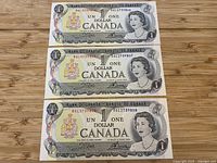 Three consecutive 1954 $1 Bank of Canada notes laid out