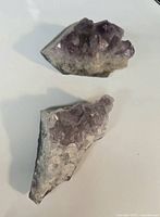 Top view showing both amethyst crystal cluster fragments with purple crystals on grey-white matrix