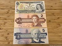 Fronts of the three uncirculated Canadian banknotes: $1 (1973), $2 (1986), $5 (1986)