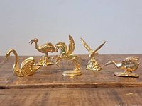Front view of all five brass animal figurines on wood surface