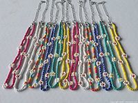 Front view of 12 assorted colour beaded daisy chain necklaces laid flat