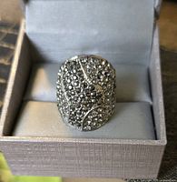 Front view of ring in box showing pavé rhinestone design and silver-tone finish