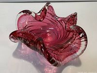 Oblique view showing cranberry glass bowl with clear ruffled rim and swirl pattern