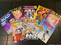 Front group shot of six of the eight MAD Magazine issues showing various cover themes