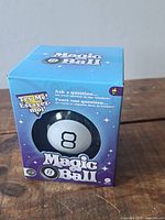 Front view of boxed Magic 8 Ball showing logo, window, and condition