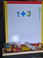 Front view of whiteboard easel showing magnetic numbers, marker and accessory tray