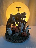 Full view of illuminated haunted house lamp with ghosts and pumpkins