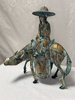 Full view of patinated metal sculpture showing scholar riding mule