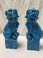 Front view of both turquoise ceramic foo dogs on plinth bases