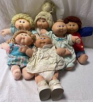 Group shot of all six dolls seated against backdrop