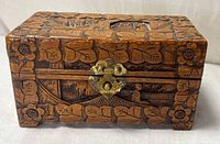 Front view of hand carved wooden box showing brass hasp and floral border