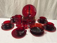 All 18 ruby red glass pieces arranged: plates, cups, bowl, creamer, vase
