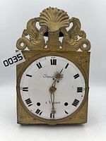 Full front view of brass wall clock showing decorative crest and enamel dial