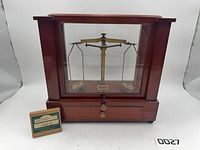 Front view of wooden apothecary scale with weight box beside