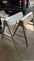 Two aluminum foldable sawhorses standing open
