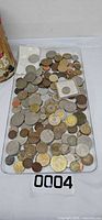 Top view of assorted foreign coins spread on tray