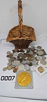 overview of basket with assorted coins spread out, visible gold-tone medal