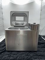 Front and side view of bread maker showing stainless steel body and open lid