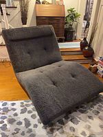 Full side view of gray ergonomic chaise lounge showing wave profile and button tufting
