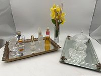 Lot overview showing two mirrored trays with perfume bottles, glass dishes, bud vase and faux flowers
