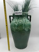 Front view of green dip glazed floor vase with ruler for scale