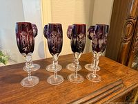 Front view of eight amethyst cut to clear crystal hock wine glasses on wooden surface