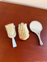 Front view of mirror and two brushes on wooden surface
