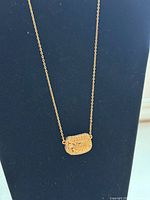 Front view of necklace with purse pendant displayed on stand