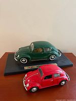 Green Maisto 1951 VW on display base with red Sunnyside 1955 VW in foreground