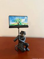 Full view of cast iron monkey bellhop card holder displaying sample card