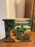 Front view showing hand-painted landscape, two doors, wooden knobs