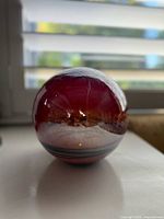 Front view of red crackle glass sphere showing red upper portion, clear mid band, small interior light dot