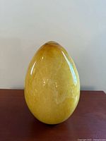 Front view of yellow Murano glass egg on surface