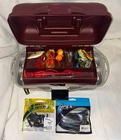 Open tackle box showing contents and two sealed lure packs placed in front