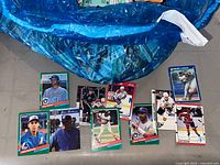 Blue plastic bag filled with numerous sports trading cards; several cards laid out showing baseball and hockey examples.
