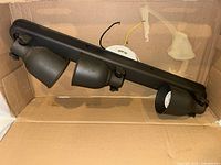 overall view of black three-head track light fixture showing wiring and mounting plate