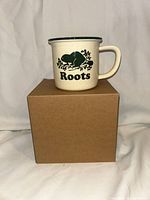 Roots ceramic mug on top of original plain cardboard box
