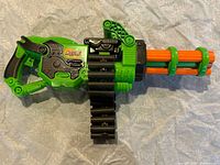 Left side view of green Adventure Force Scorpion blaster showing six rotating barrels, folding carry handle and black ammo belt