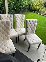 Four light beige tufted dining chairs on patio