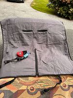 Full view of grey quilted car seat protector laid out with slits and zipper, treat pouch and collar placed on top