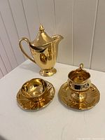 coffee pot, creamer on saucer, sugar bowl on saucer