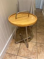 Front view of round wood top side table with metal legs and handle