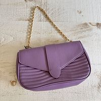 Front view of lavender shoulder bag showing quilted front, flap closure, gold chain