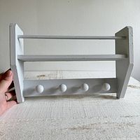 Front view of painted wood shelf showing shelves and knob hooks