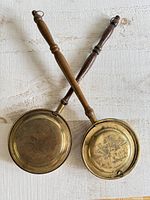 Both brass bed warmers crossed to show full form, handles and pans