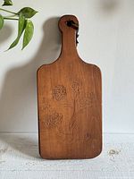 Front of board showing carved floral motif and handle with leather tie