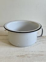 Side view of enamel chamber pot showing handle and overall shape