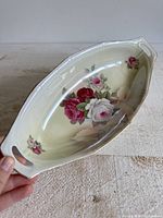 Oblique view of porcelain serving tray showing floral design, handles, and iridescent glaze