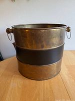 Front view of brass planter showing faux leather band and right side loop handle