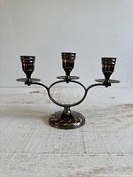 Front view of copper tone three-cup candlestick holder